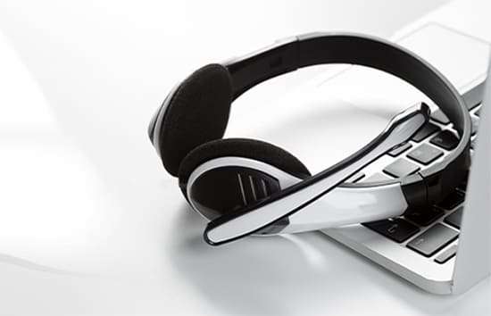 A black and white headset rests on a laptop keyboard, ready for communication—contact us for laptop repair help!